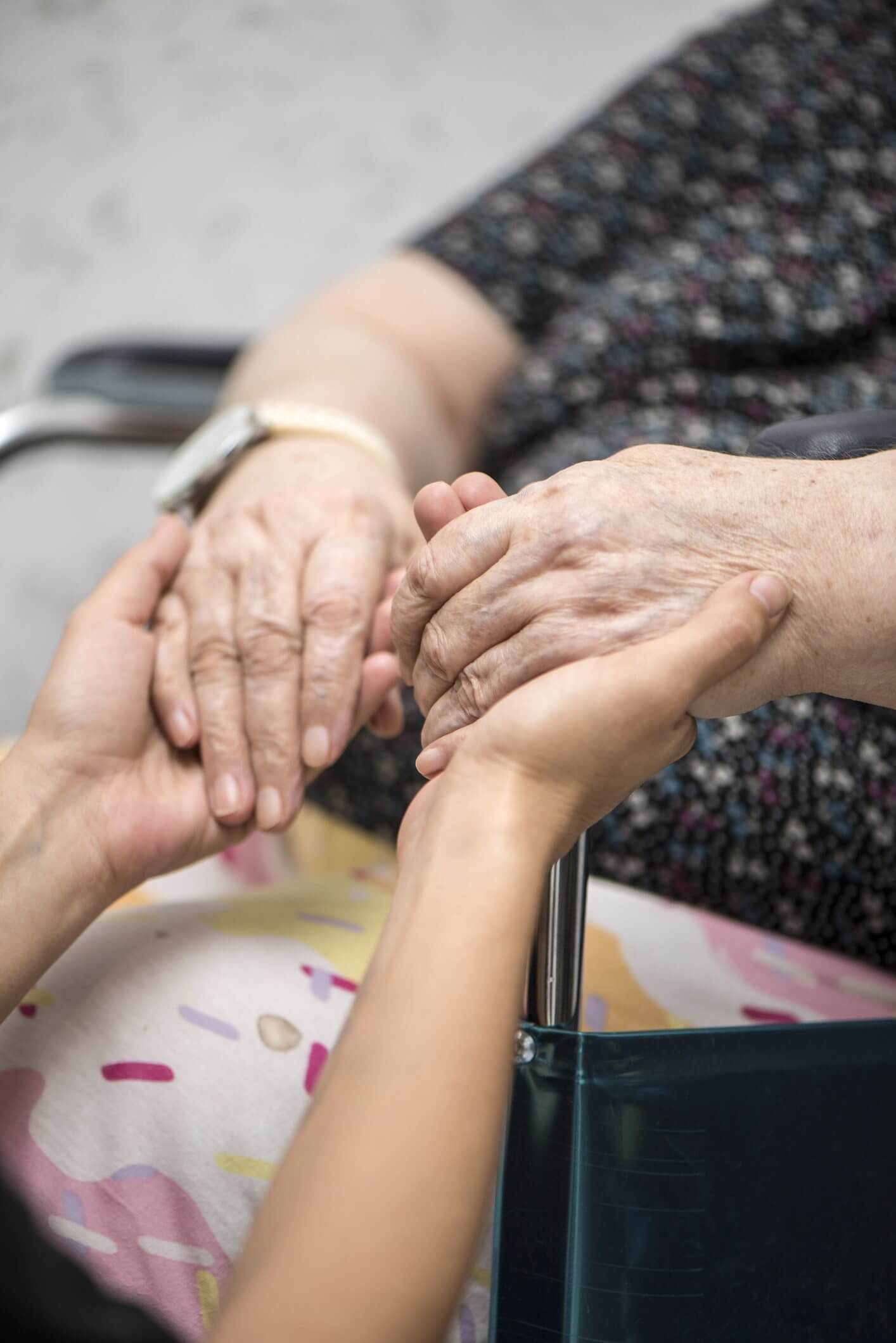 Elderly hands gently held by younger ones, symbolizing care.