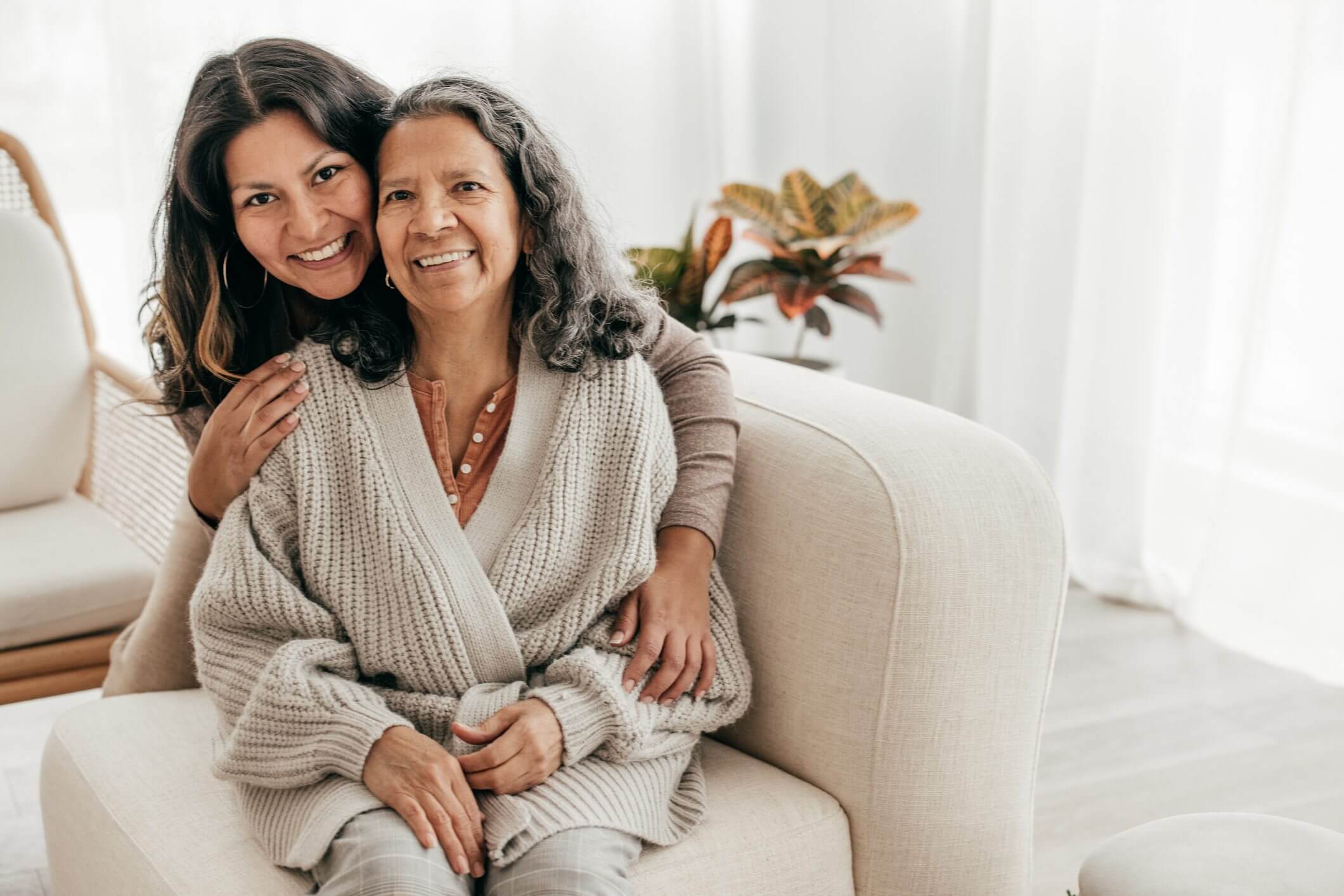 Two women embracing happily on a cozy sofa.
