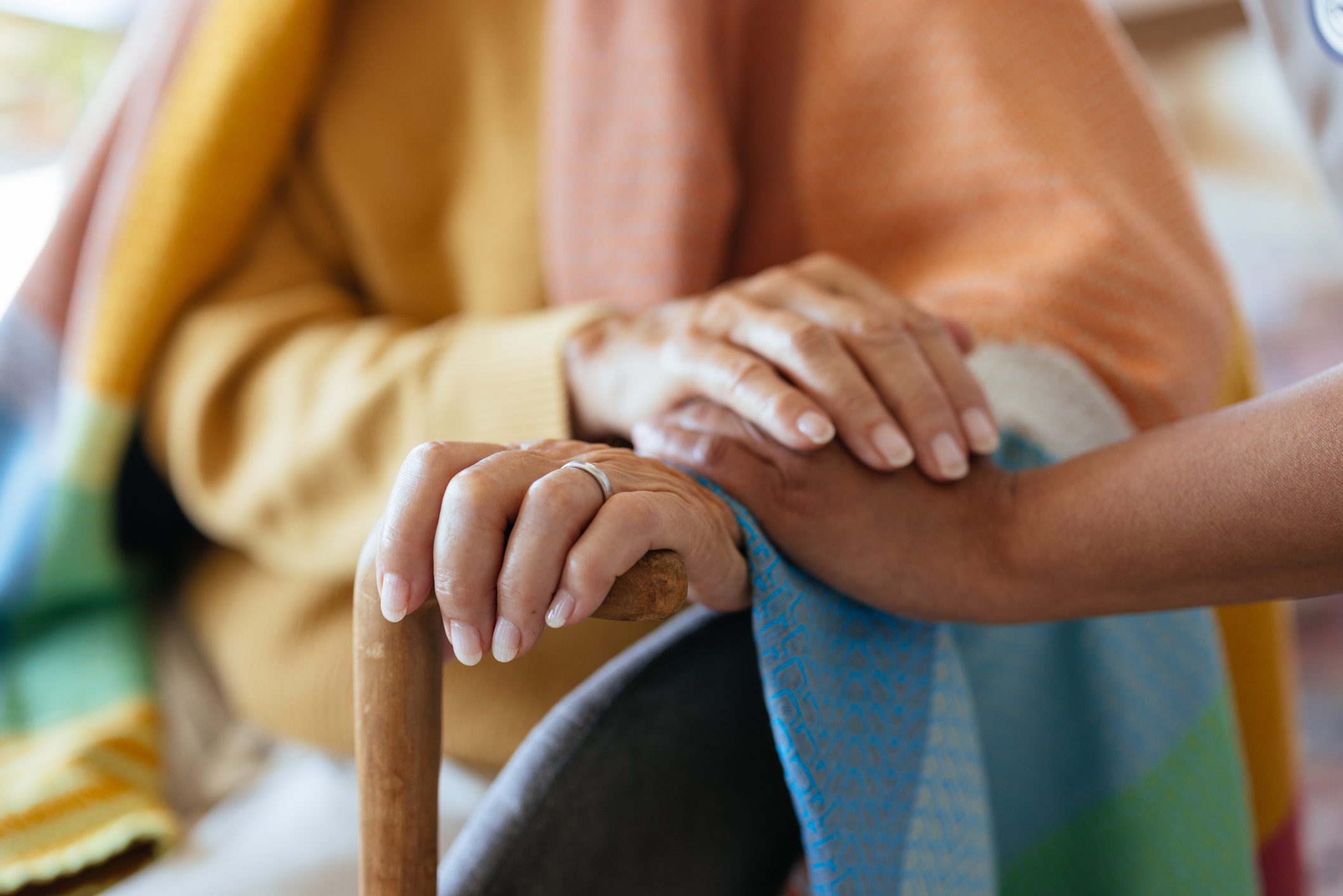 Hands of an elderly person being gently held for support and comfort.
