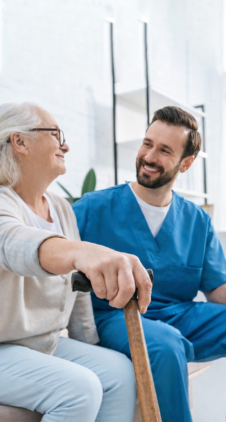 Caregiver smiling with elderly woman holding cane